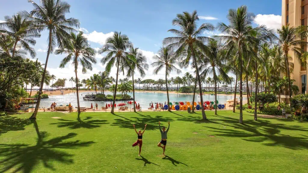 Guests on the palm-lined lawn beside the lagoon