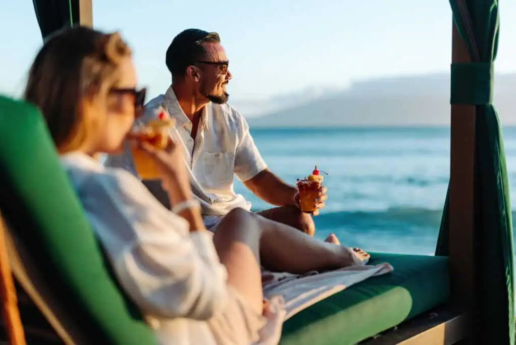 Man and woman sipping drinks in beachside cabana