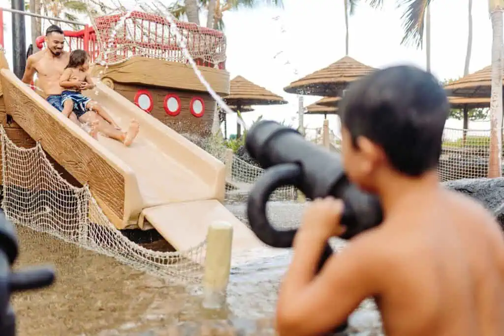 Father and sons playing on pool pirate ship