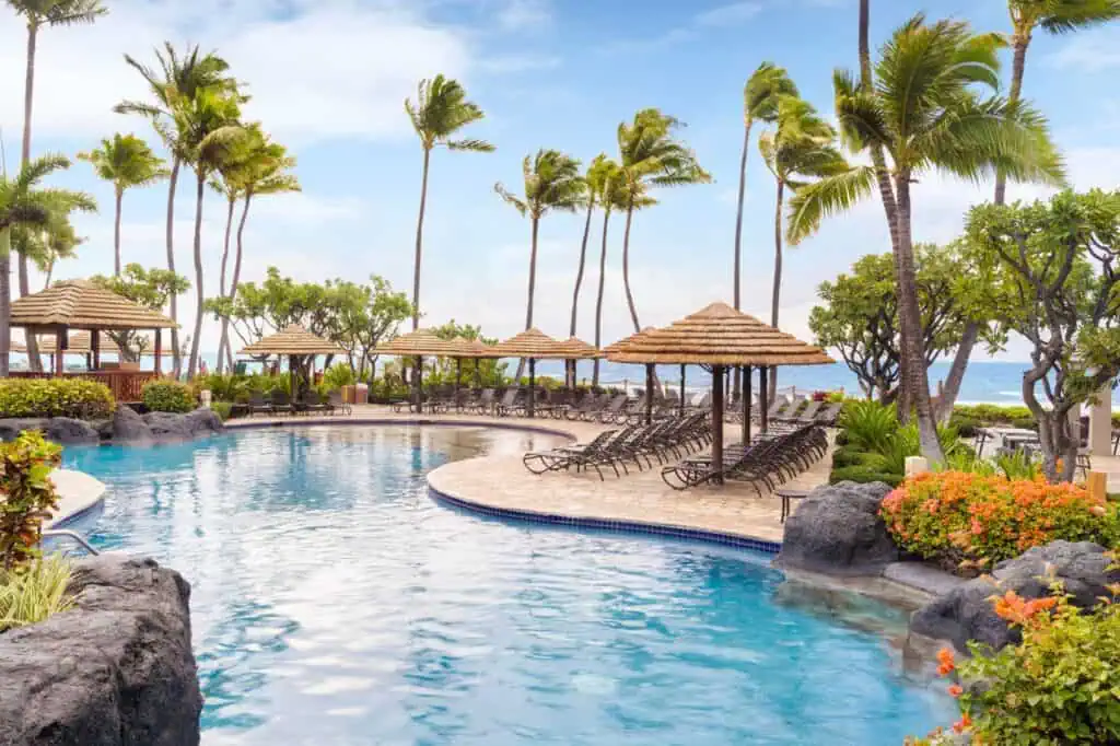 Resort pool, loungers, umbrellas, view of beach