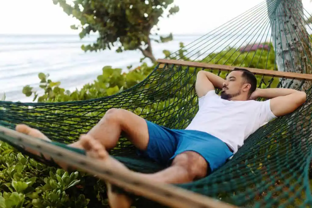 Man laying in beachside hammock