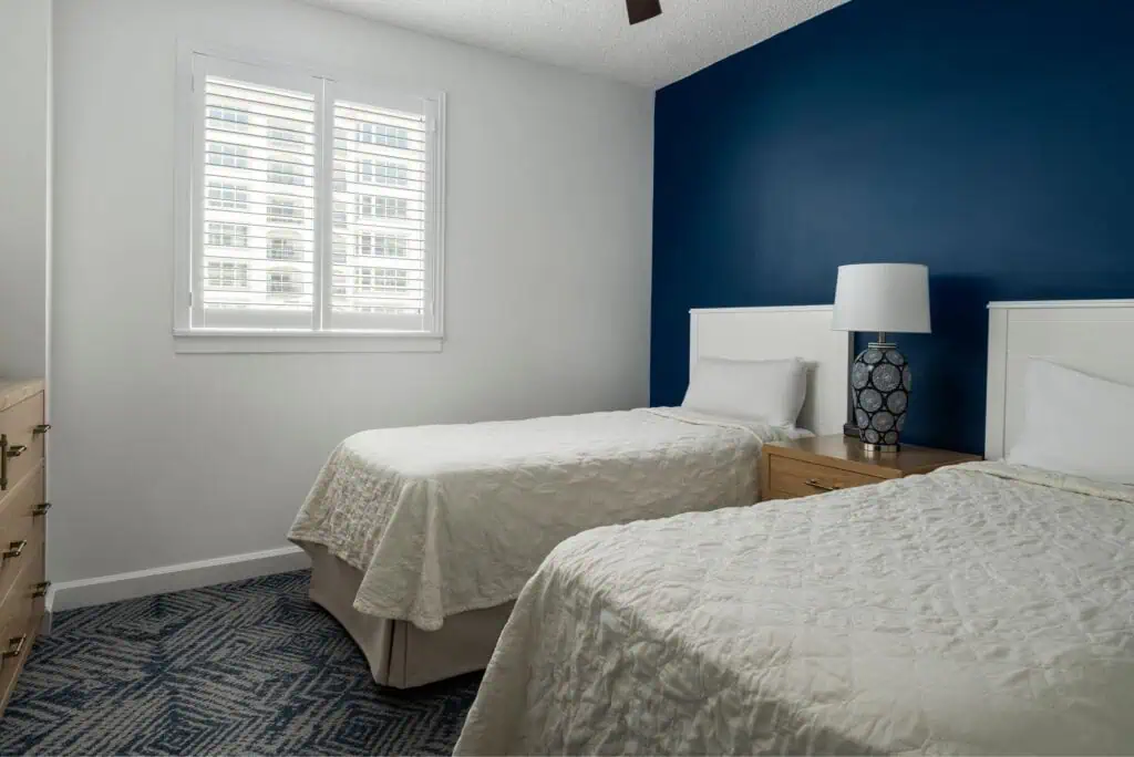 Two twin beds, lamp, dresser, and ceiling fan