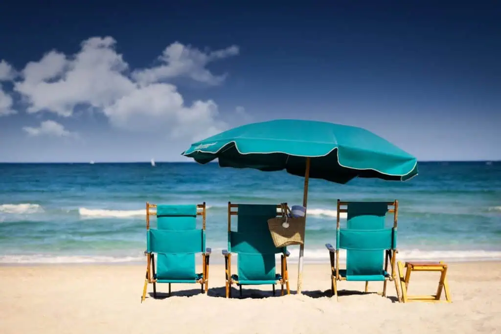 Beach chairs, umbrella on sand near ocean